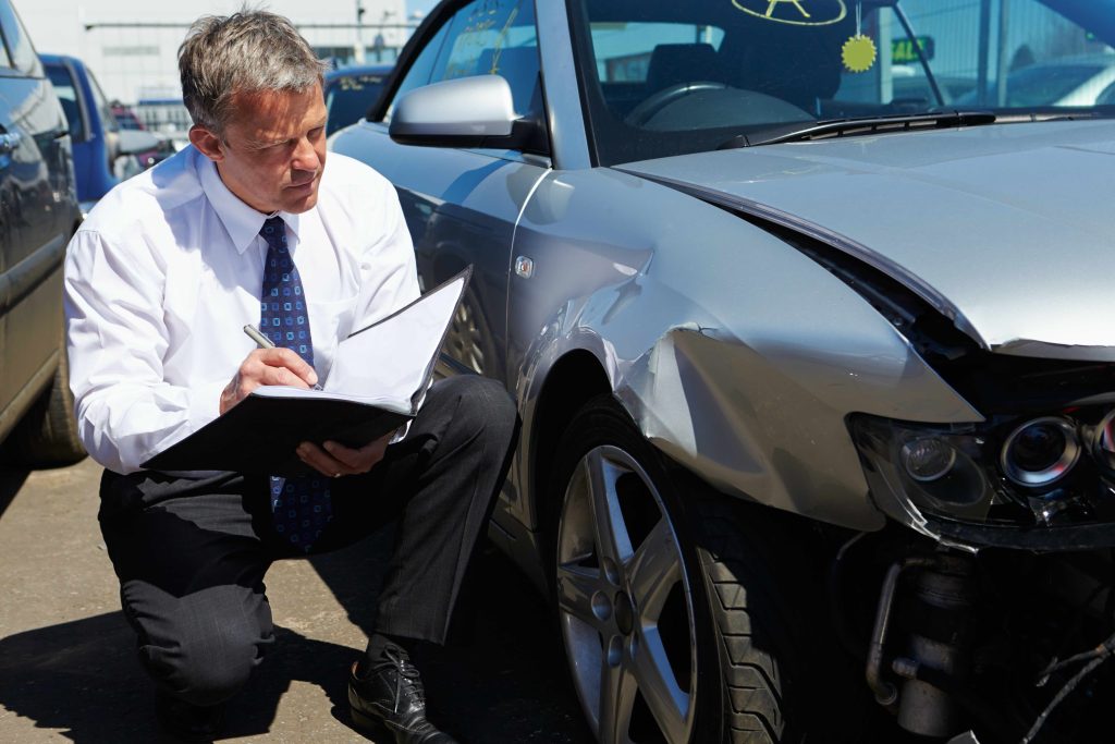 Insurance Adjustor evaluating the value of the damage to a totaled vehicle.
